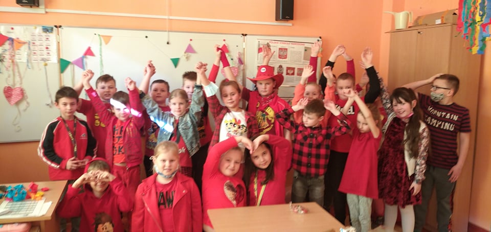 Fotografia przedstawia uczniów klasy drugiej ubranych na czerwono i trzymających serca z papieru.