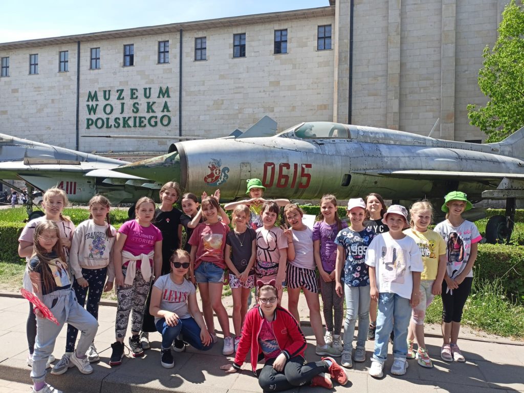 Fotografia przedstawia uczniów stojących przy wielkim modelu samolotu w muzeum Wojska Polskiego.