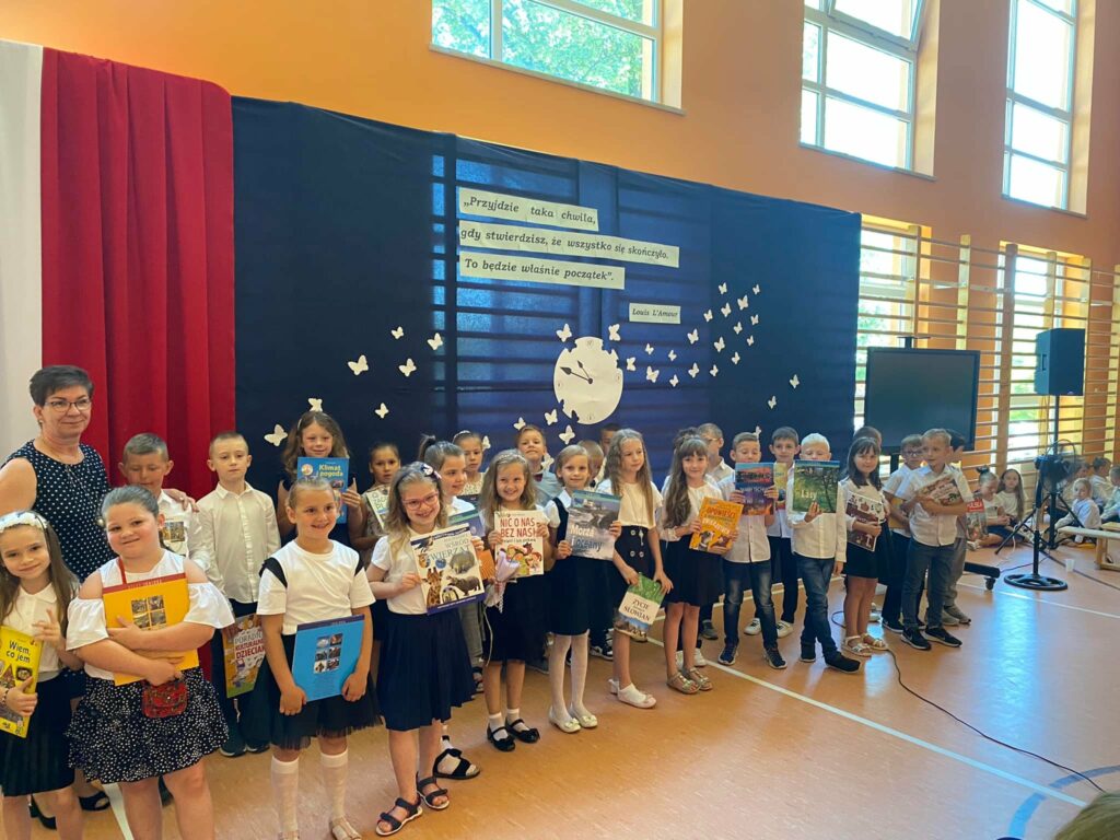 Fotografia przedstawia uczniów klasy pierwszej trzymających nagrody książkowe.