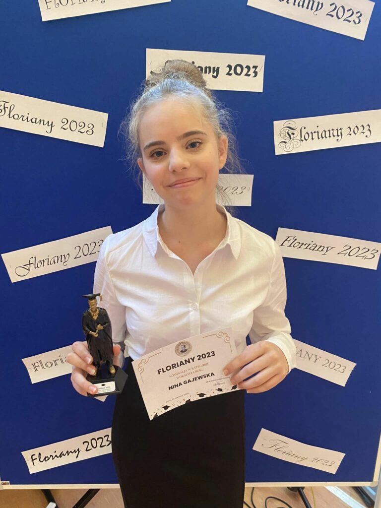 Fotografia przedstawia uczennicę Ninę Gajewską trzymającą nagrodę "Floriana" w rękach.