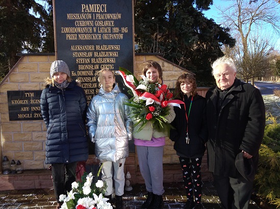 Fotografia przedstawia uczniów stojących pod pomnikiem pamięci w Łężtynie.