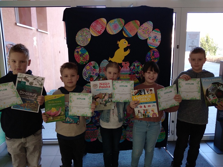 Fotografia przedstawia piątkę uczniów trzymających dyplomy i nagrody za udział w konkursie.