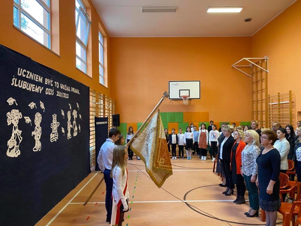 Zdjęcie przedstawia społeczność szkolną podczas śpiewania Hymnu Szkoły.