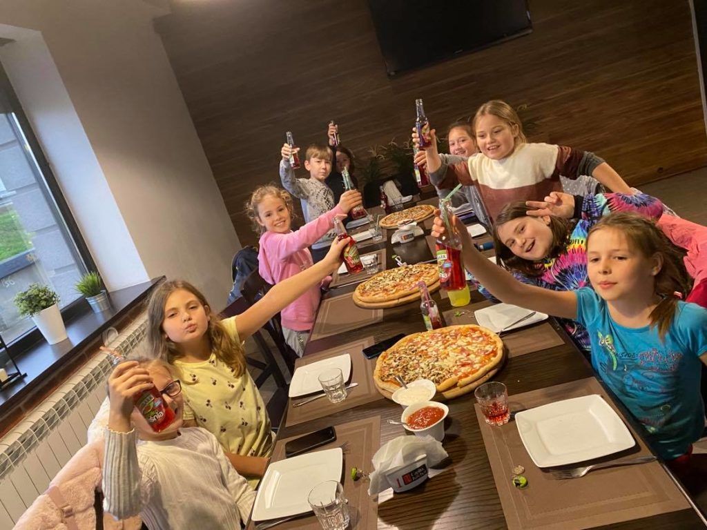 Zdjęcie przedstawia uczniów jedzących pizzę w pizzerii ANGELA.